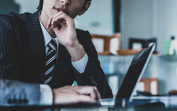 パソコンの前で悩む人物イメージ